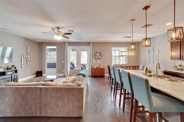 living room with ceiling fan, sink, a textured ceiling, and hardwood / wood-style flooring