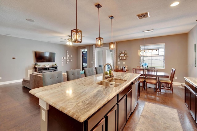 kitchen with a textured ceiling, ceiling fan, sink, a center island with sink, and dishwasher