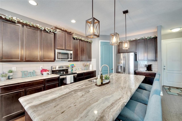 kitchen featuring a center island with sink, backsplash, sink, and stainless steel appliances