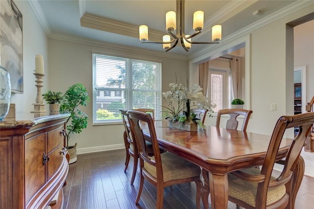 dining space with a chandelier, dark wood-type flooring, a raised ceiling, and ornamental molding