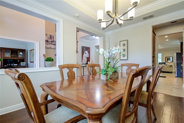 dining room featuring hardwood / wood-style flooring, crown molding, and an inviting chandelier