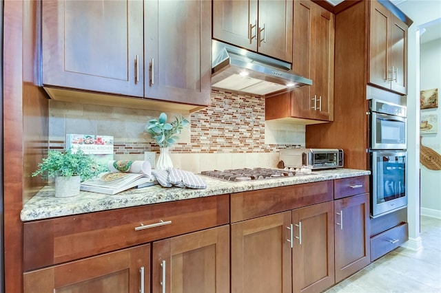 kitchen with decorative backsplash, light stone counters, light tile patterned floors, and stainless steel appliances