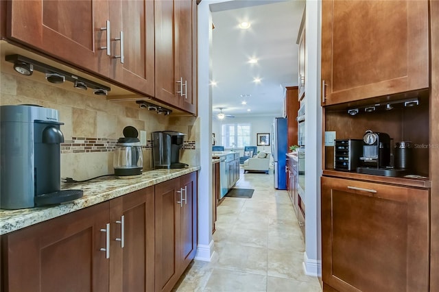 kitchen with tasteful backsplash, light stone countertops, and ceiling fan