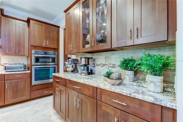 kitchen featuring decorative backsplash, light stone counters, crown molding, and double oven