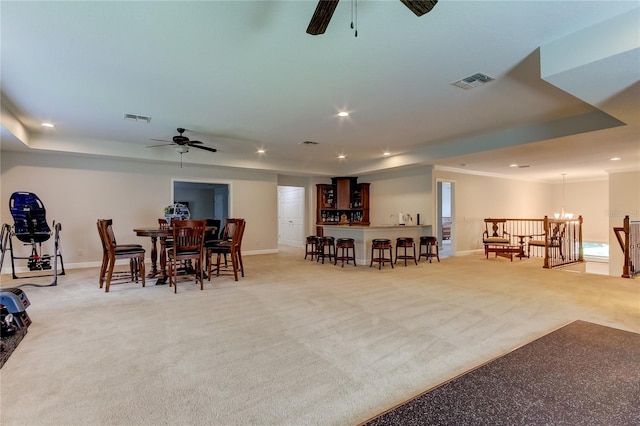 dining room with ceiling fan with notable chandelier, light carpet, and bar area