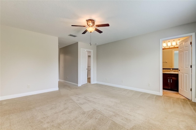 spare room with ceiling fan, light colored carpet, and sink