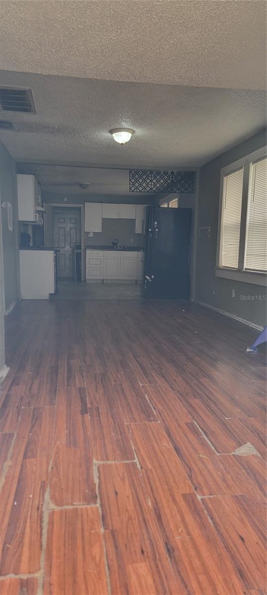 basement with dark hardwood / wood-style floors, black refrigerator, and a textured ceiling