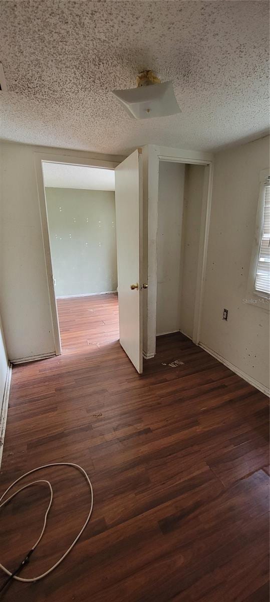 empty room featuring dark wood-type flooring and a textured ceiling