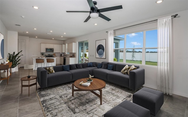 living room featuring a water view, light tile patterned floors, and ceiling fan