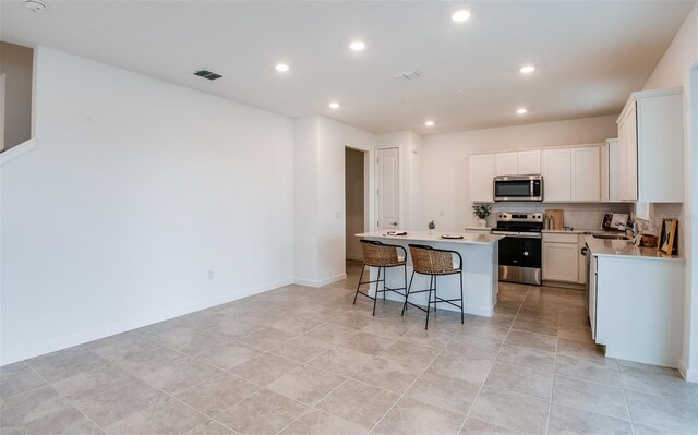 kitchen with a center island, white cabinetry, backsplash, and appliances with stainless steel finishes