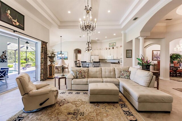 living room with decorative columns, crown molding, light tile patterned flooring, a tray ceiling, and an inviting chandelier