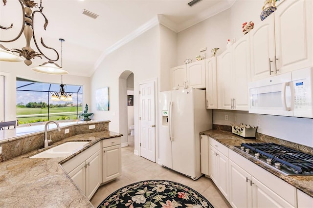 kitchen with white appliances, lofted ceiling, light tile patterned floors, sink, and decorative light fixtures