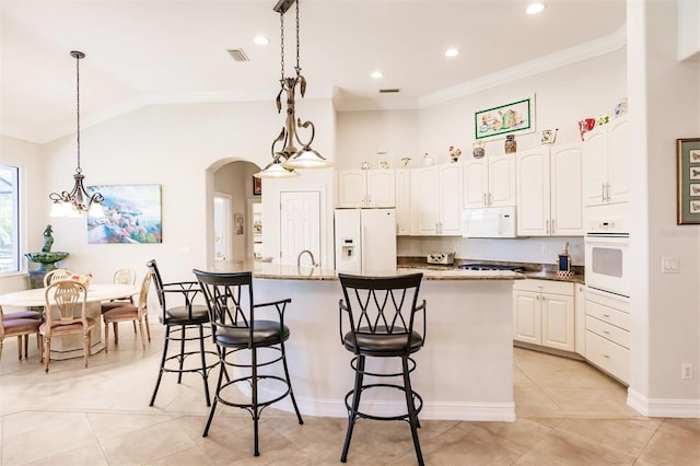 kitchen with a center island with sink, white appliances, dark stone countertops, light tile patterned floors, and white cabinets