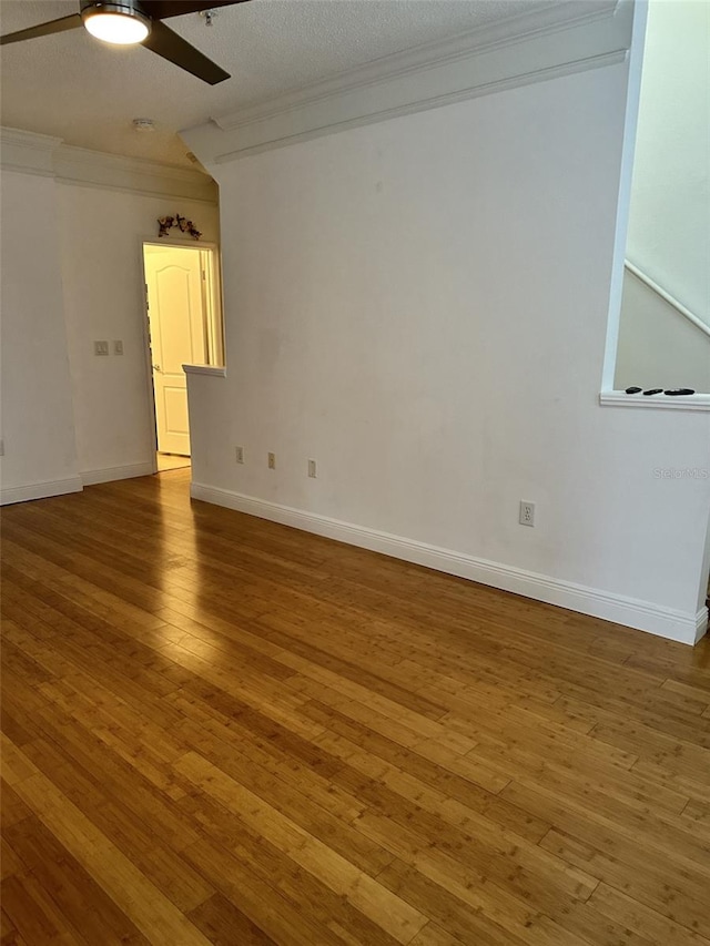 spare room with a textured ceiling, wood-type flooring, ceiling fan, and crown molding