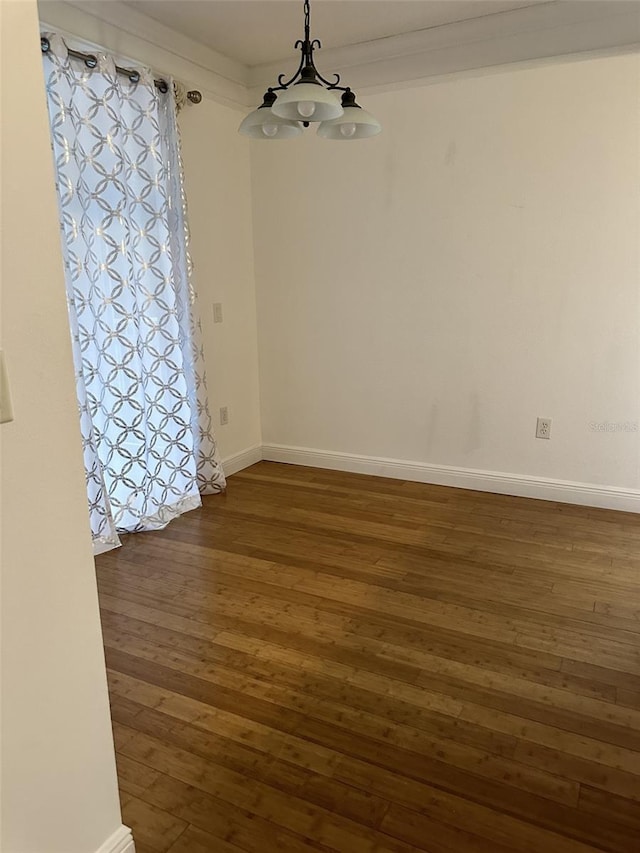 unfurnished room featuring dark wood-type flooring, crown molding, and a chandelier