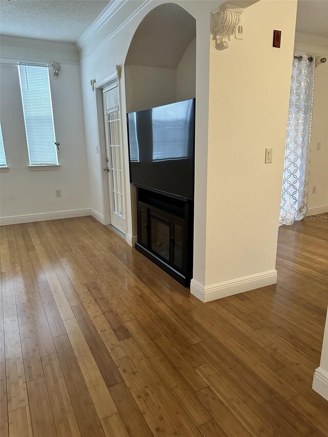 unfurnished living room with a textured ceiling, hardwood / wood-style floors, and ornamental molding