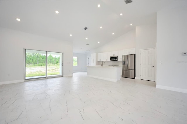 unfurnished living room featuring sink and high vaulted ceiling