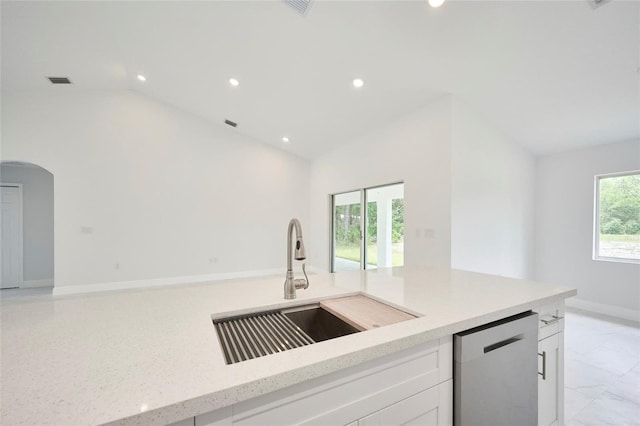 kitchen featuring lofted ceiling, sink, white cabinetry, light stone counters, and dishwasher