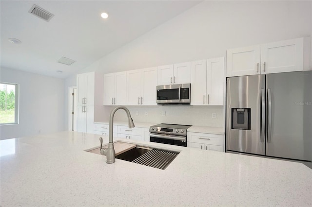 kitchen with sink, backsplash, stainless steel appliances, light stone counters, and white cabinets