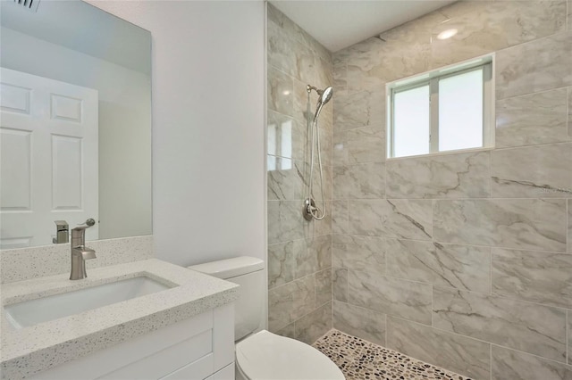 bathroom with vanity, toilet, and a tile shower