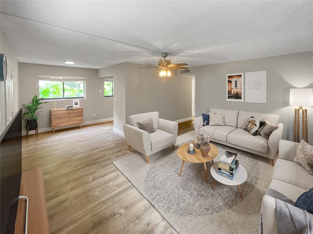 living room featuring hardwood / wood-style flooring, ceiling fan, and a textured ceiling