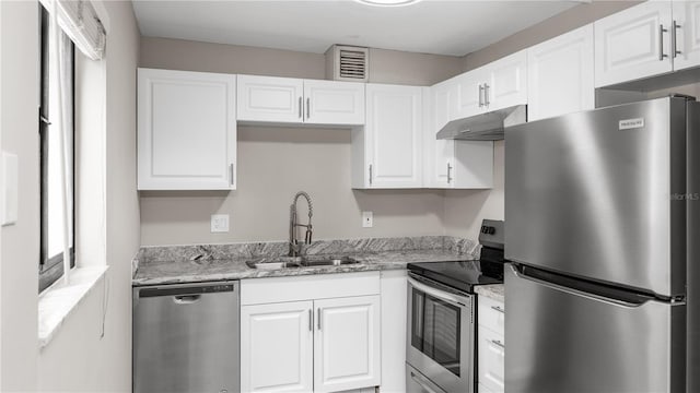 kitchen with stainless steel appliances, light stone countertops, sink, and white cabinets