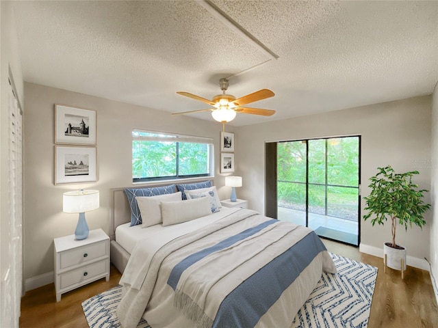 bedroom featuring multiple windows, ceiling fan, access to outside, and wood-type flooring