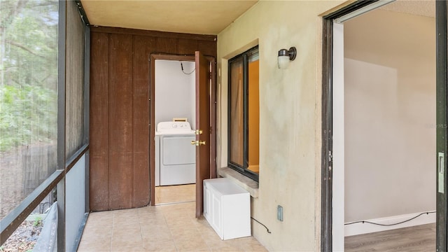 hallway with washer / clothes dryer and light tile patterned floors