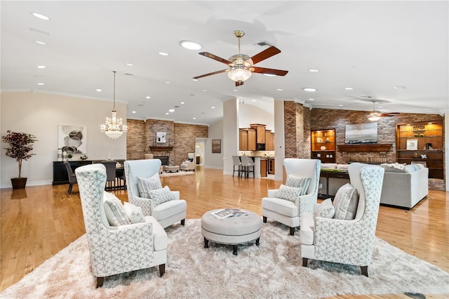 living room with a fireplace, ceiling fan with notable chandelier, light hardwood / wood-style floors, and ornamental molding