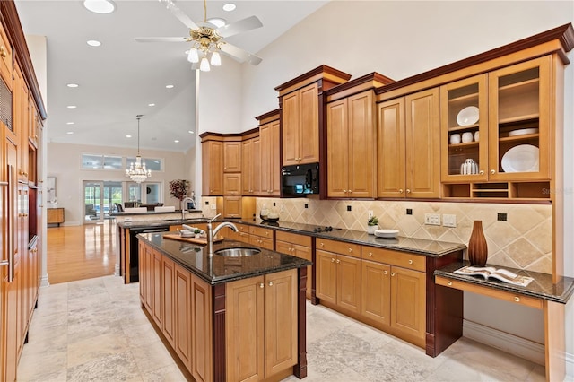 kitchen featuring dark stone counters, ceiling fan with notable chandelier, sink, black appliances, and decorative light fixtures