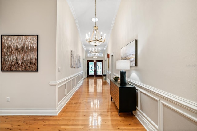 entryway featuring french doors, light hardwood / wood-style flooring, an inviting chandelier, and ornamental molding