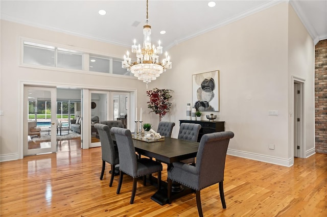 dining room featuring light wood-type flooring, french doors, crown molding, and a chandelier