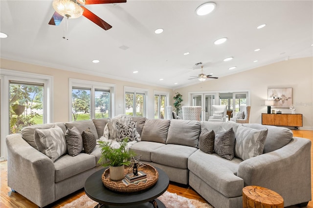 living room with light wood-type flooring, vaulted ceiling, a wealth of natural light, and ornamental molding