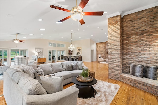 living room featuring a brick fireplace, ceiling fan with notable chandelier, light hardwood / wood-style flooring, and lofted ceiling