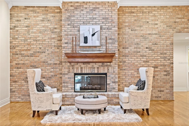 sitting room featuring light wood-type flooring, crown molding, and brick wall