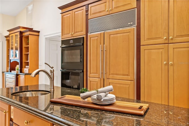 kitchen with sink, dark stone counters, paneled refrigerator, and black double oven