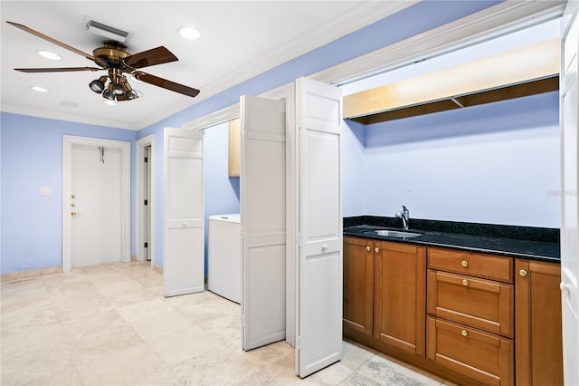 kitchen featuring ceiling fan, ornamental molding, sink, and washer / clothes dryer