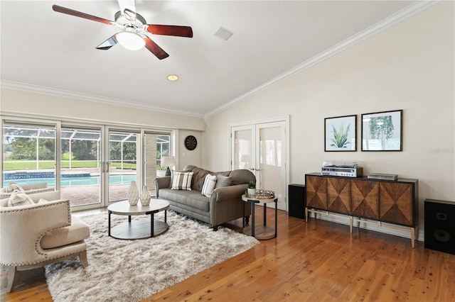 living room with hardwood / wood-style floors, ceiling fan, ornamental molding, and vaulted ceiling