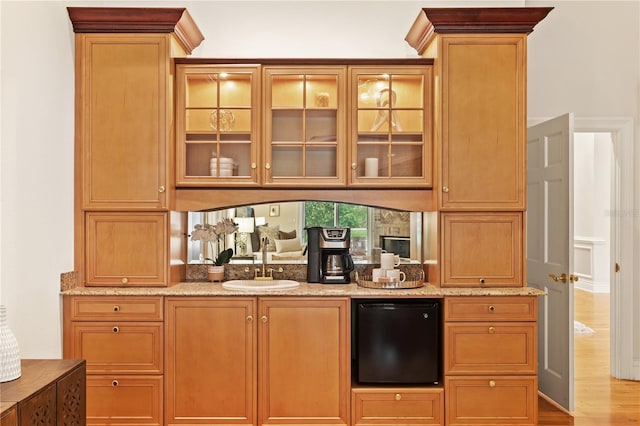 bar featuring light hardwood / wood-style floors, light stone countertops, sink, and fridge