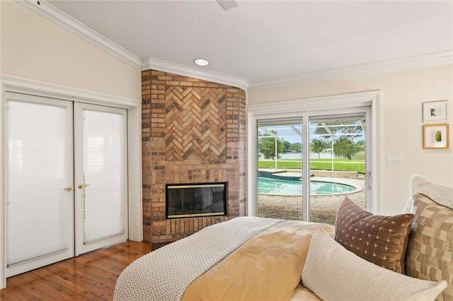 bedroom featuring ornamental molding, access to outside, hardwood / wood-style flooring, a fireplace, and lofted ceiling