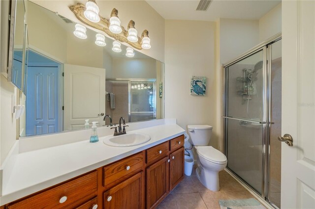 bathroom featuring tile patterned floors, vanity, toilet, and a shower with door