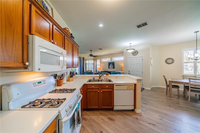 kitchen with sink, decorative light fixtures, kitchen peninsula, white appliances, and light hardwood / wood-style floors