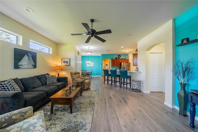 living room with ceiling fan, light hardwood / wood-style flooring, and a textured ceiling