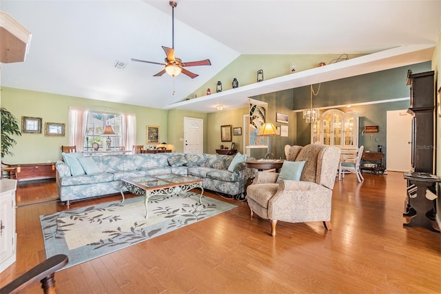 living room with hardwood / wood-style floors, ceiling fan with notable chandelier, and high vaulted ceiling