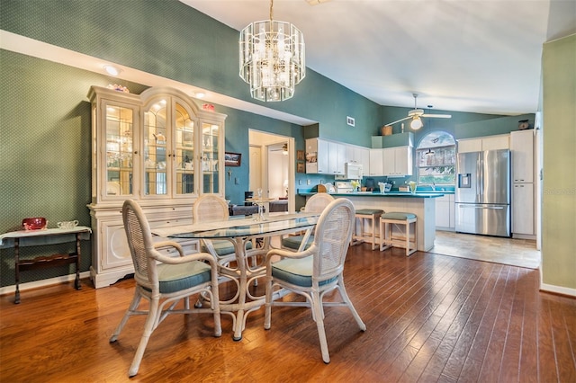 dining room featuring dark wood-type flooring, ceiling fan with notable chandelier, and high vaulted ceiling