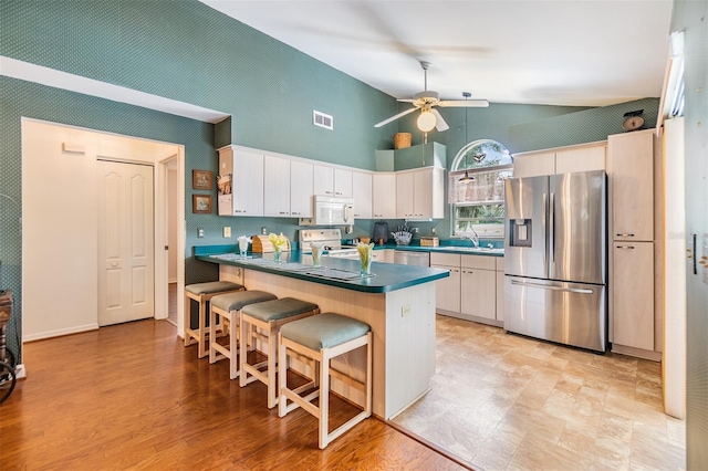 kitchen with appliances with stainless steel finishes, light hardwood / wood-style floors, white cabinetry, ceiling fan, and a kitchen bar