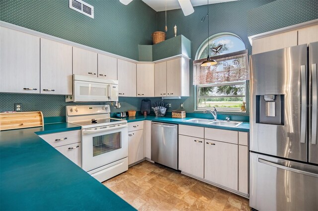 kitchen with a towering ceiling, appliances with stainless steel finishes, ceiling fan, and sink