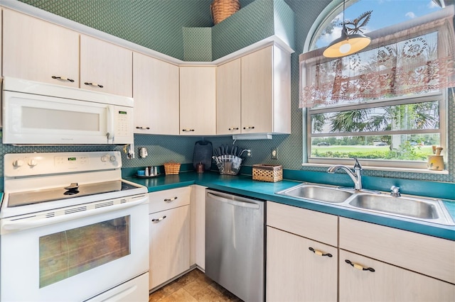 kitchen with white appliances, pendant lighting, light brown cabinetry, and sink