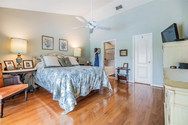 bedroom with ceiling fan, connected bathroom, high vaulted ceiling, and light hardwood / wood-style floors