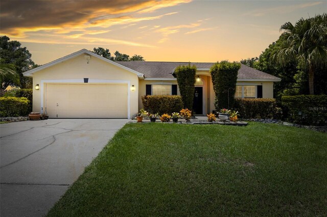 ranch-style home with a garage and a lawn